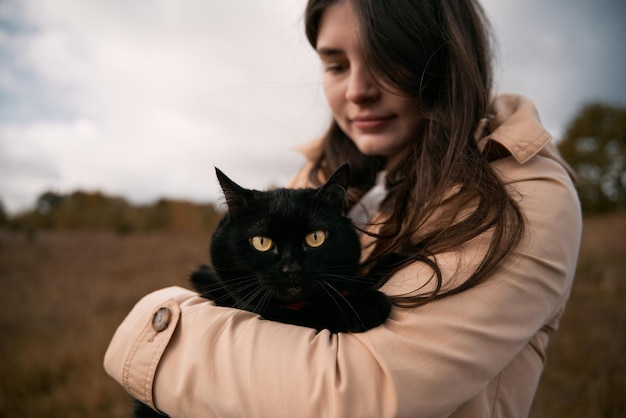 Photo beautiful girl is hugging her cat concept of weekend in the countryside area with your lovely pet brunette woman has great time with her black shorthair cat