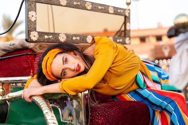 A beautiful girl is resting in a carriage on Jemaa el-Fna square. Marrakech, Morocco