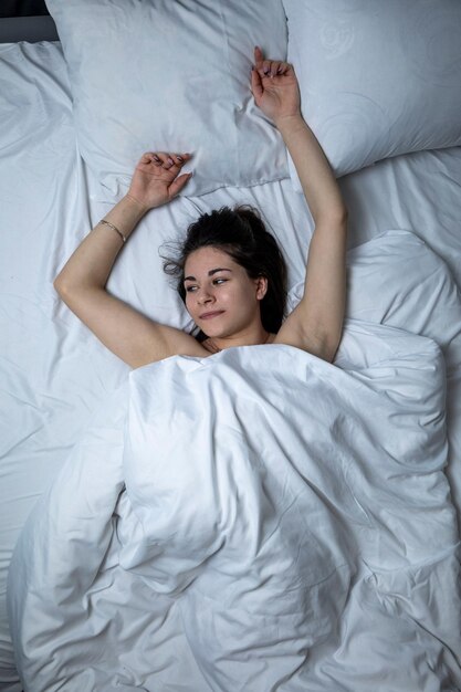 A beautiful girl is sleeping in a bed with a white sheet