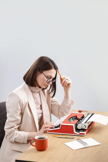 A beautiful girl is typing on a typewriter and thinking working on a book a script