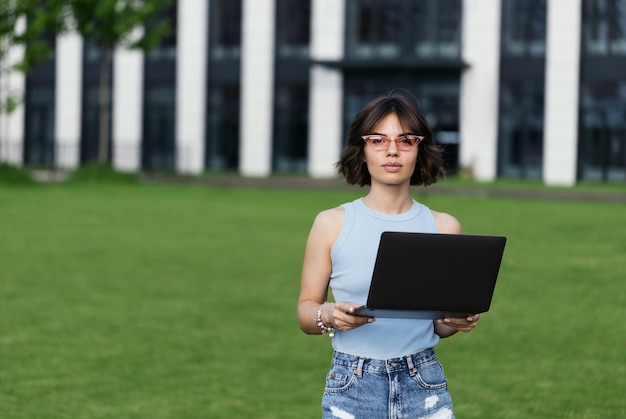 A beautiful girl is working on a laptop in the park