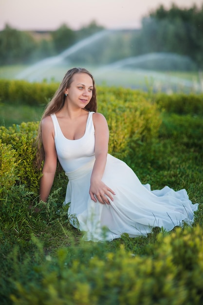 Beautiful girl in lavender She is wearing a long dress and a big hat Place for text The fountain