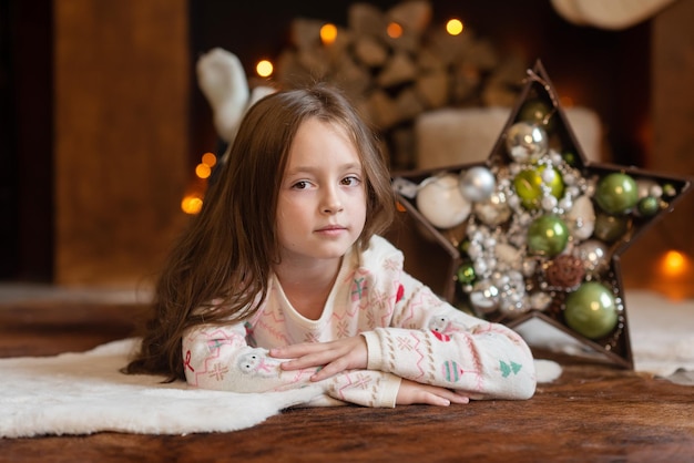 A beautiful girl lies on a wardrobe trunk in a New Years sweater against the background