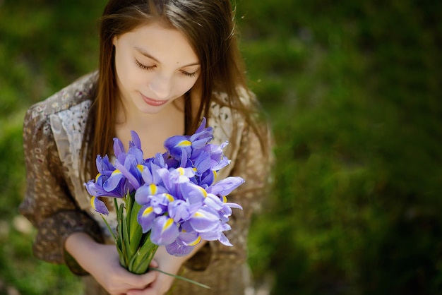 Beautiful girl looks at a bouquet of spring flowers of irises