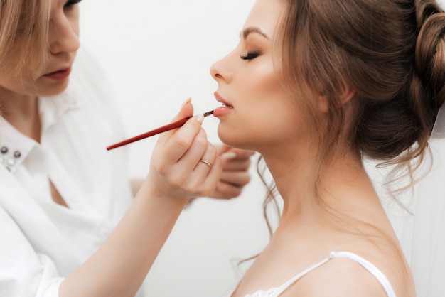 Beautiful girl makeup artist makes make-up and paints her lips in a professional beauty salon