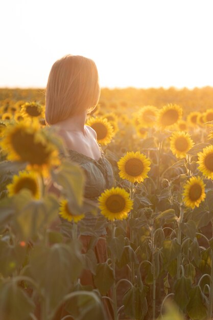 Beautiful girl meets the sunset in a field of sunflowers