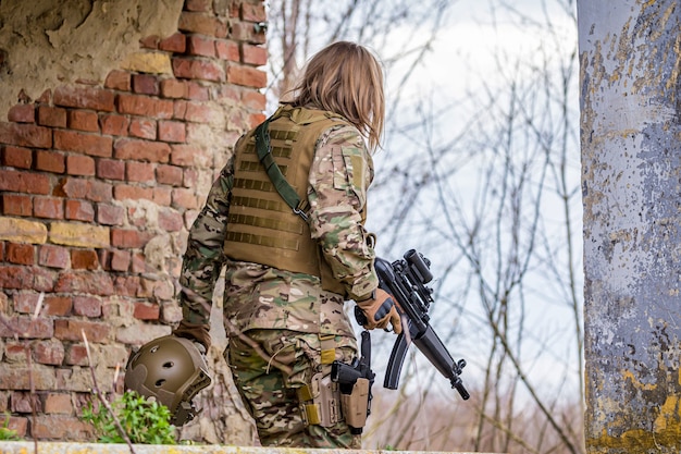 Beautiful girl in military uniform with an airsoft gun