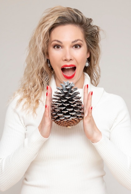 A beautiful girl model with a beautiful smile holds two big pine cones, whoop and shout