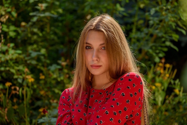 Beautiful girl in nature. girl in a magnificent red dress. Natural brown hair of a beautiful girl.