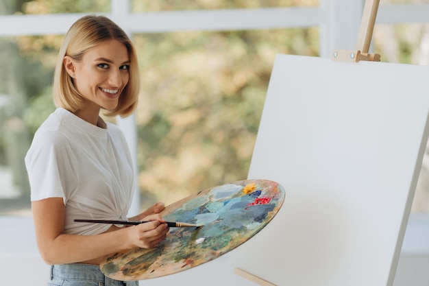 A beautiful girl paints on a canvas in a university classroom