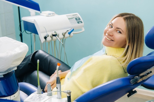 A beautiful girl patient smiles sitting in a dentist's chair