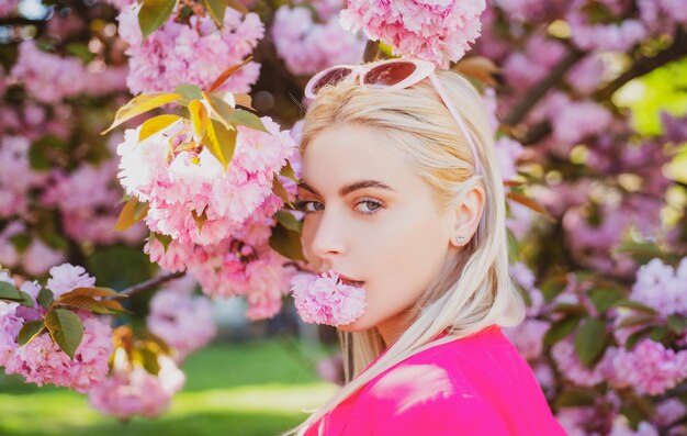 Beautiful girl in pink flowers in summer blossom park Portrait of young woman in the flowered garden