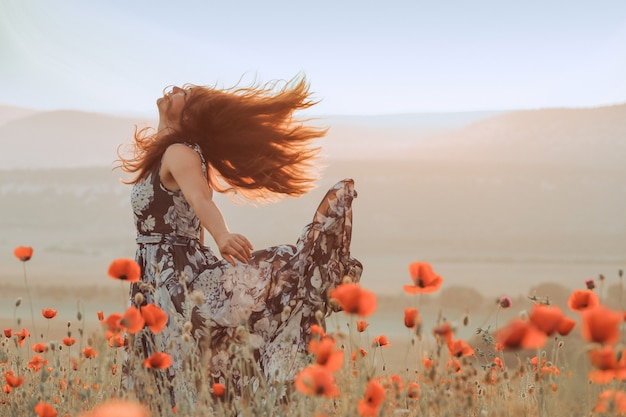 Beautiful girl in a poppy field at sunset. concept of freedom