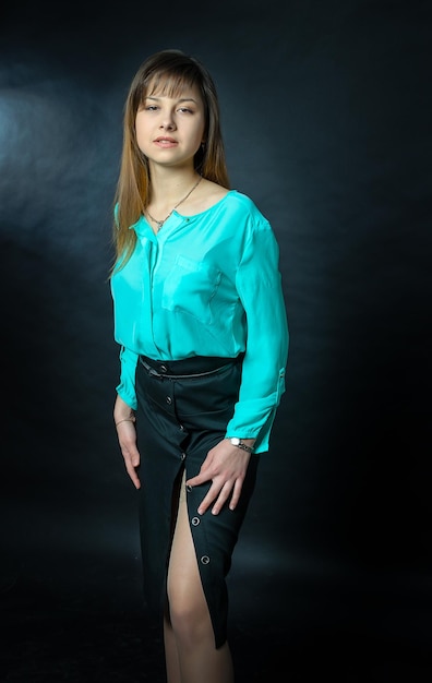 A beautiful girl poses in the studio against a dark background