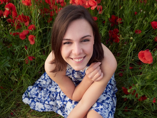 Beautiful girl posing in poppy field on sunny day