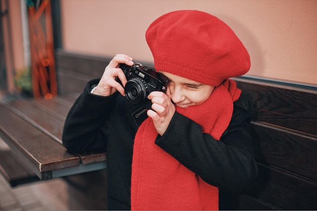 Beautiful girl in a red beret and scarf takes pictures on the city street. High quality photo