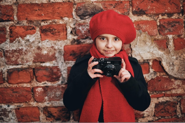 Beautiful girl in a red beret and scarf takes pictures on the city street. High quality photo