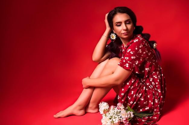 Beautiful girl in a red dress on a red background with flowers