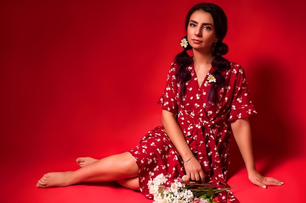 Beautiful girl in a red dress on a red background with flowers