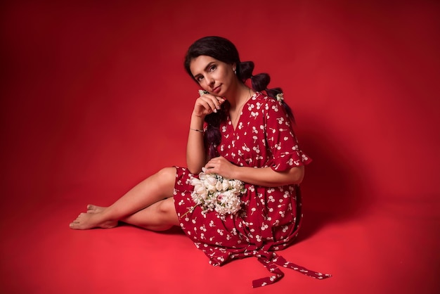 Beautiful girl in a red dress on a red background with flowers