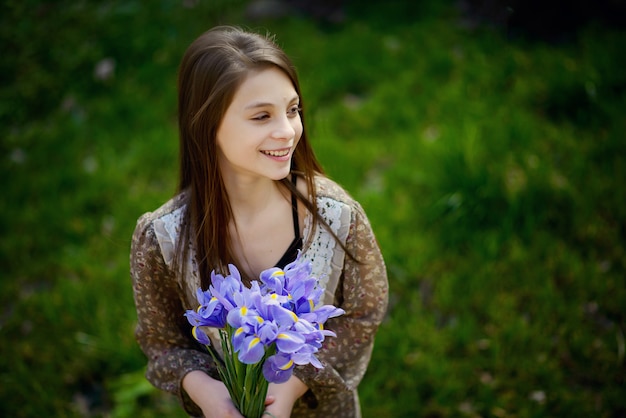 Beautiful girl rejoices and smiles with a bouquet of spring flowers in her hands. Soft focus.