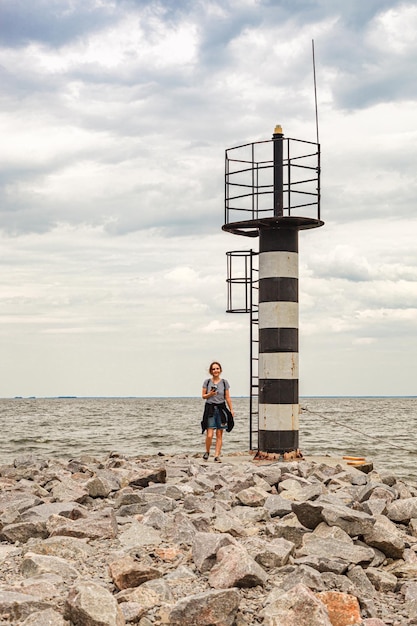 Beautiful girl on the sea overlooking the lighthouse and blue sky with clouds closeup