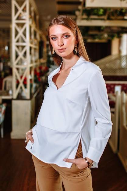 A beautiful girl showing fashionable clothes against the backdrop of the restaurant scenery Clothes for the showroom