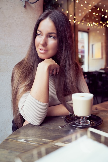 Beautiful girl sits in cafe in Christmas holidays