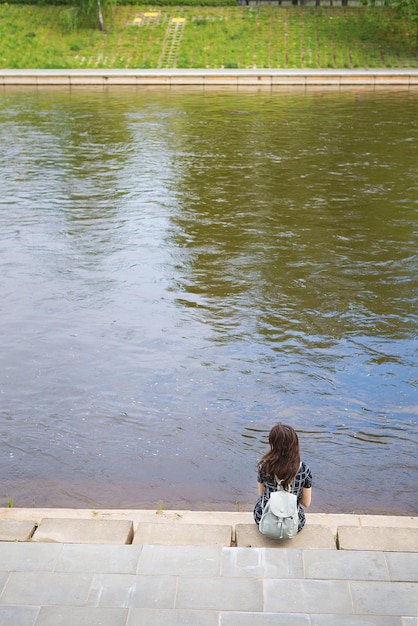 Beautiful girl sits and looks at the river Vilnius Lithuania