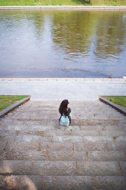 Beautiful girl sits and looks at the river Vilnius