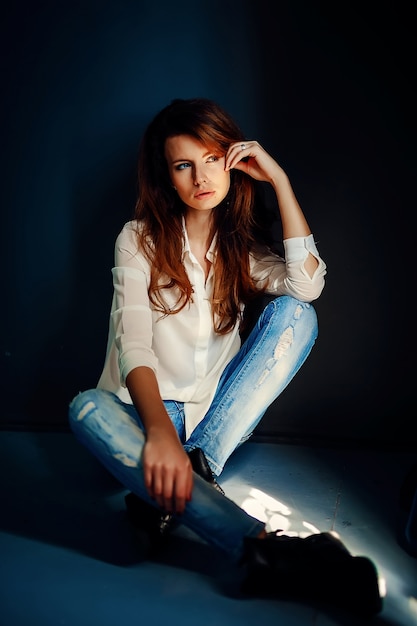 Beautiful girl sitting on floor in darkness