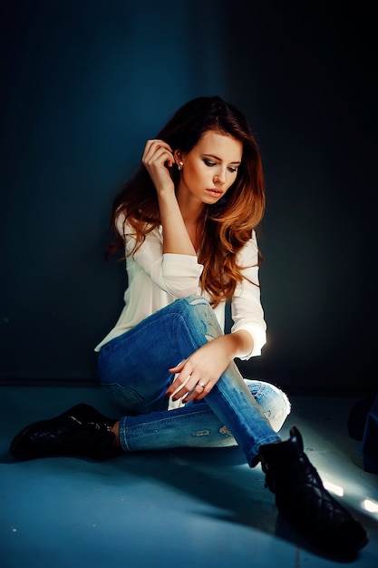 Beautiful girl sitting on floor in darkness