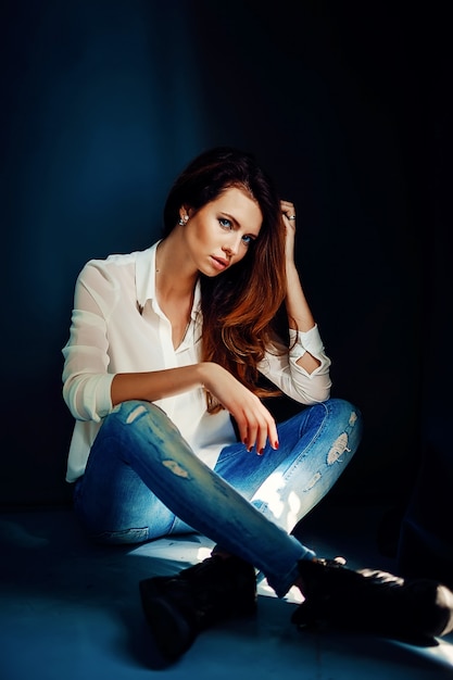 Beautiful girl sitting on floor in darkness