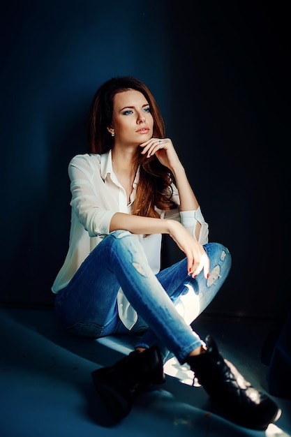 Beautiful girl sitting on floor in darkness