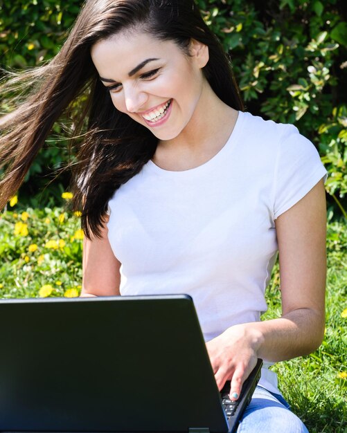 Beautiful girl sitting in the park with a laptop