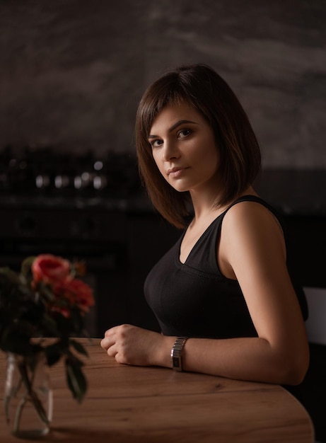 Beautiful girl sitting at a table in a dark kitchen