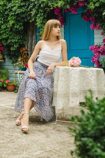 Beautiful girl sitting at a table near the house