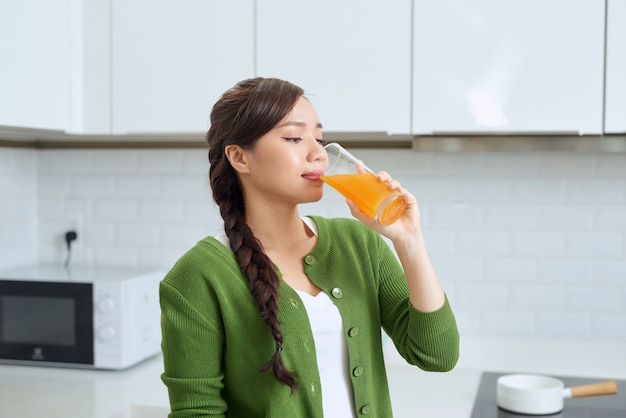 Beautiful girl smiling standing hold orange glass juice kitchen