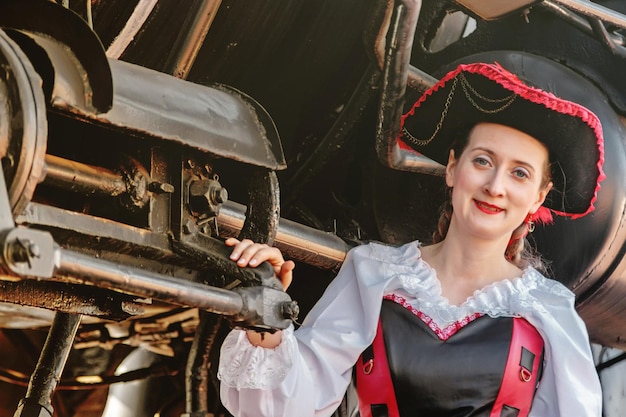 Photo beautiful girl in a steampunk suit on a background of an old train