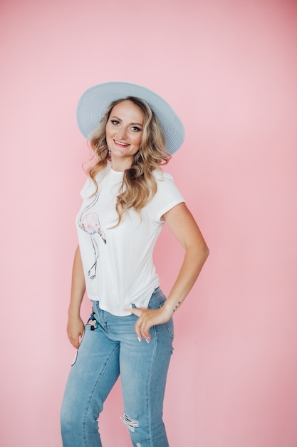 Beautiful girl in summer clothes rejoices, picture isolated on pink wall