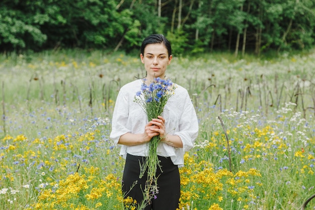 Beautiful girl among the summer field with wildflowers