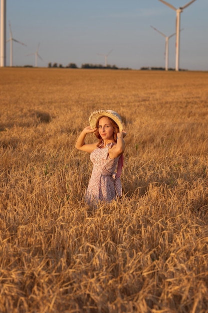 Beautiful girl at sunset in a wheat field with windmills to generate electricity Concept of renewable energy love for nature electricity Renewable energy