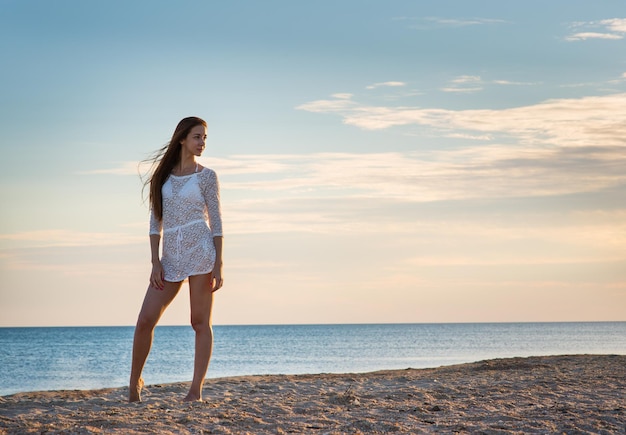 Beautiful girl in a swimsuit on the beach at sunset