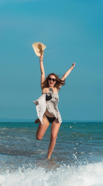 A beautiful girl in a swimsuit in summer on the seashore happily having fun on the water with emotions