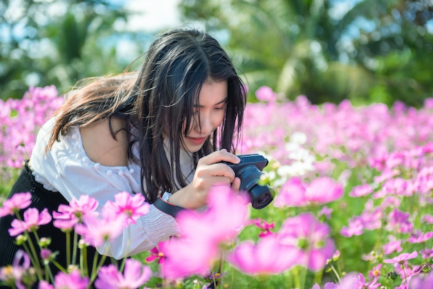 Beautiful girl take a photo to cosmos flower in garden.