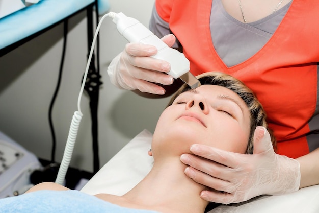 A beautiful girl takes the procedure of ultrasonic facial cleaning in a beauty salon