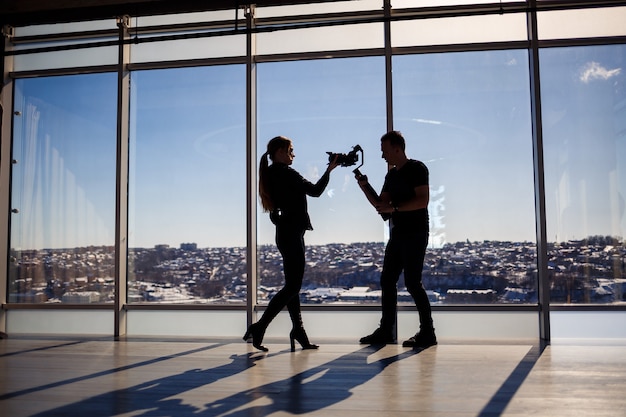 A beautiful girl takes a selfie on her phone against the background of panoramic windows in a skyscraper