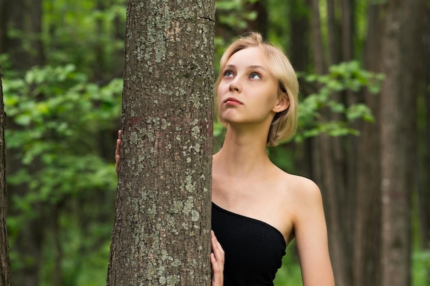 Photo beautiful girl next to the tree in the forest