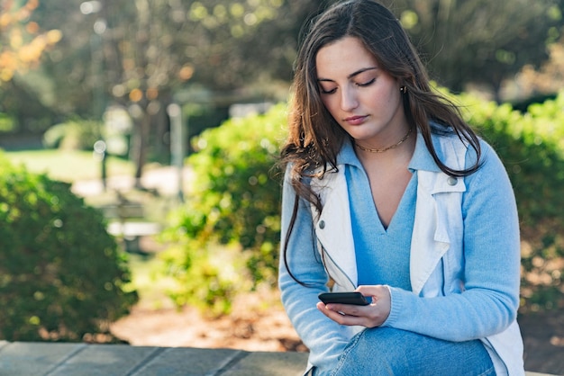 Beautiful girl using her mobile phone in a park