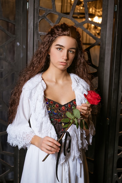 Beautiful girl in a vintage style dress with a red rose in her hands